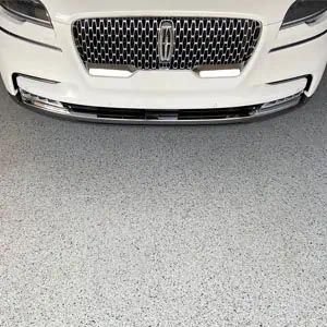 A white Lincoln parked on a gray full flake epoxy and polyaspartic coated concrete floor.